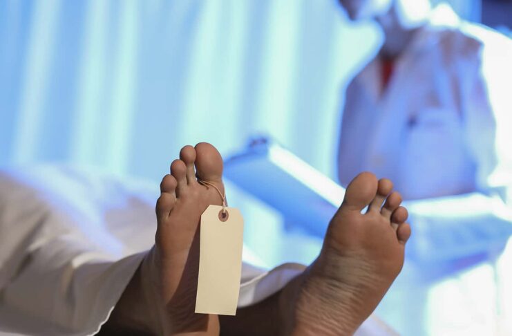 Medical examiner or forensic scientist with dead man